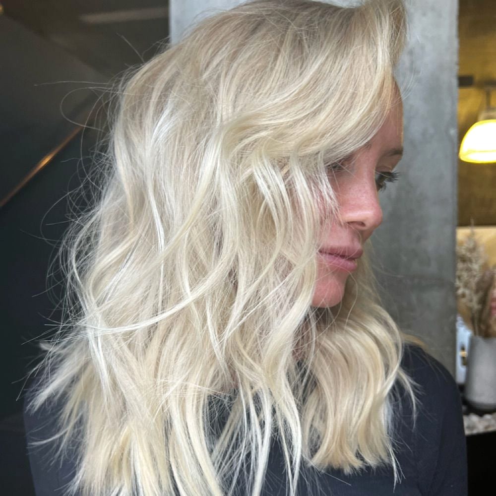 Side profile of wavy platinum blonde hair in the salon